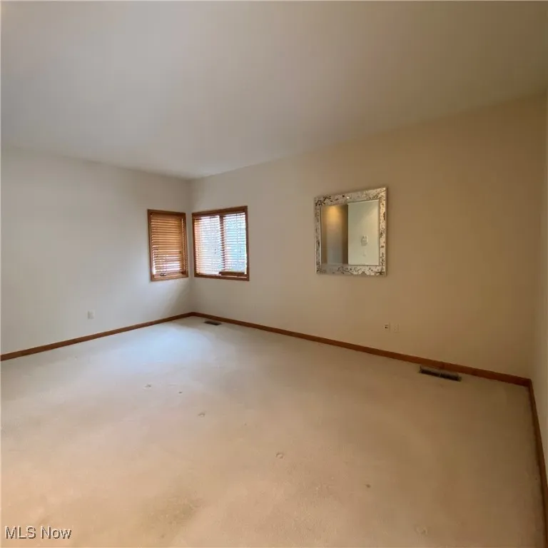Carpeted spare room featuring baseboards