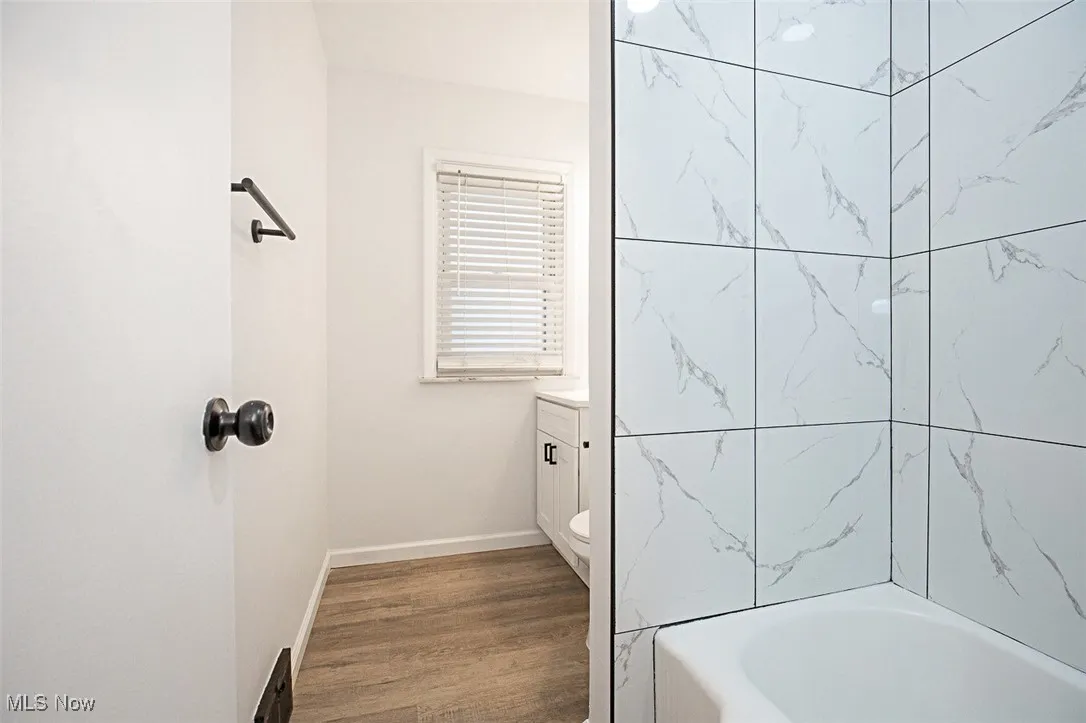 Full bath featuring wood finished floors, vanity, and bathtub / shower combination