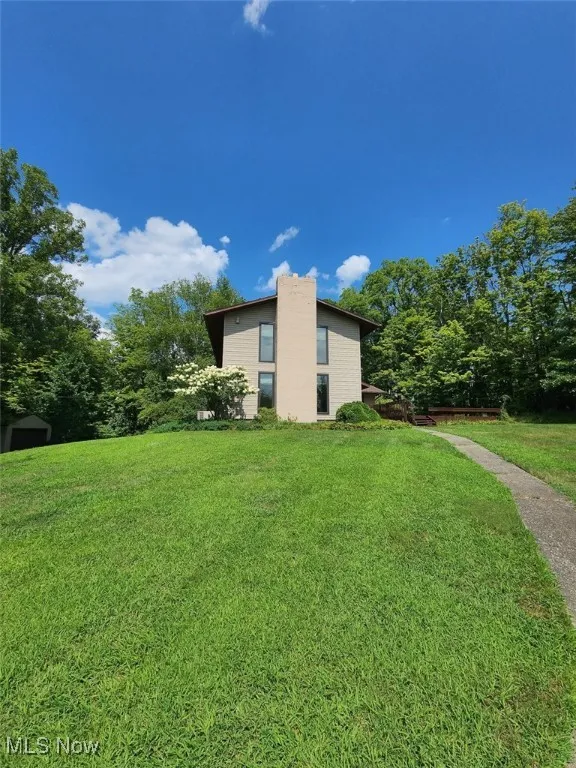 View of home's exterior featuring a lawn and a chimney