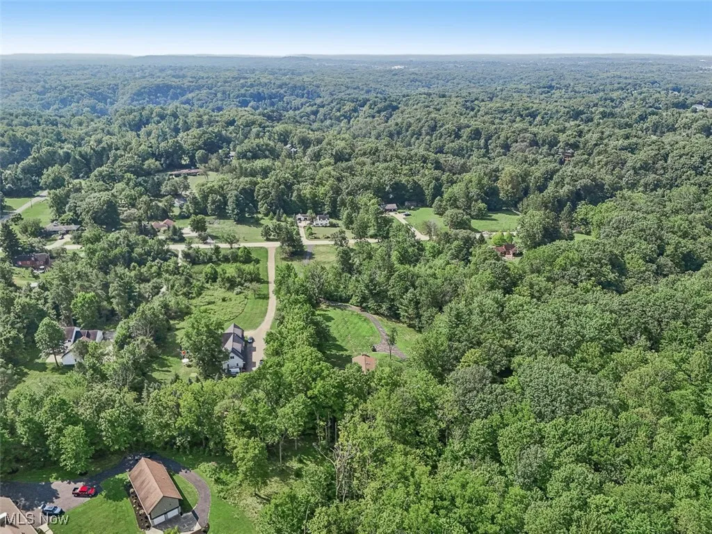 Aerial view of property and surrounding area with a forest