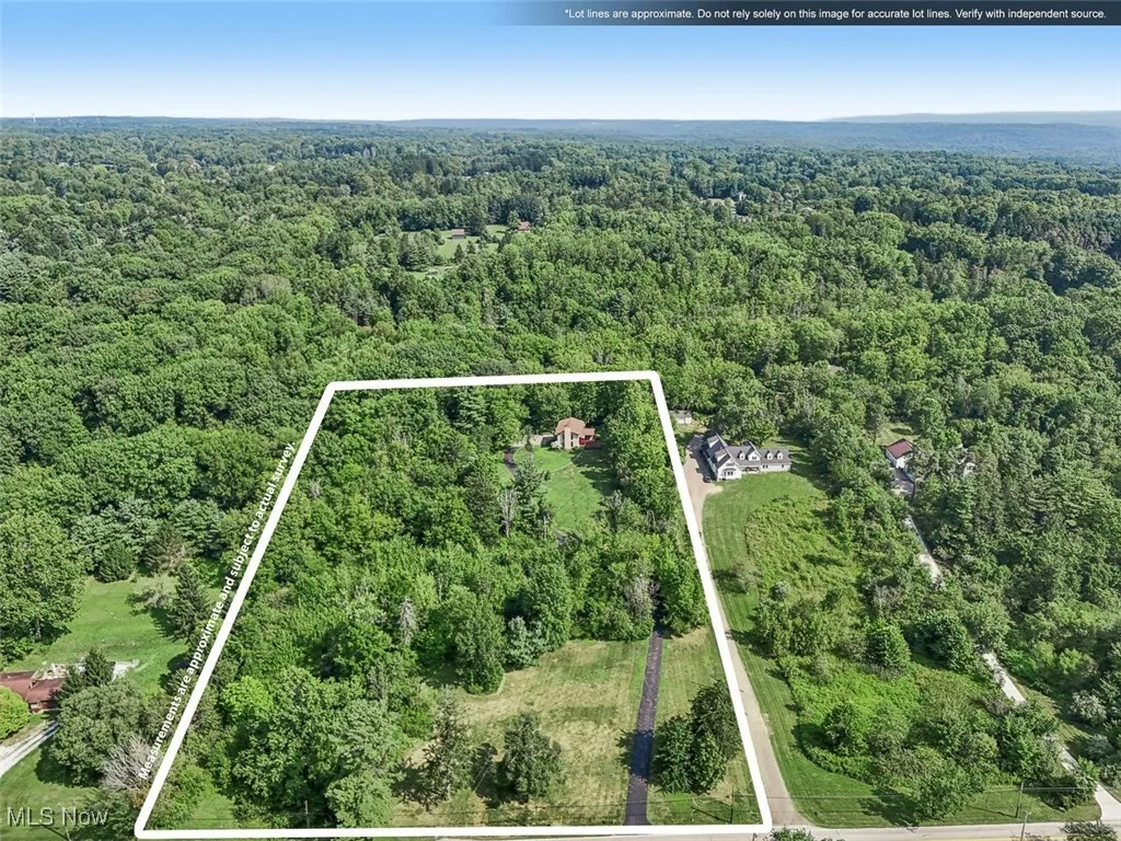 Aerial view of property and surrounding area featuring a heavily wooded area and property boundaries highlighted