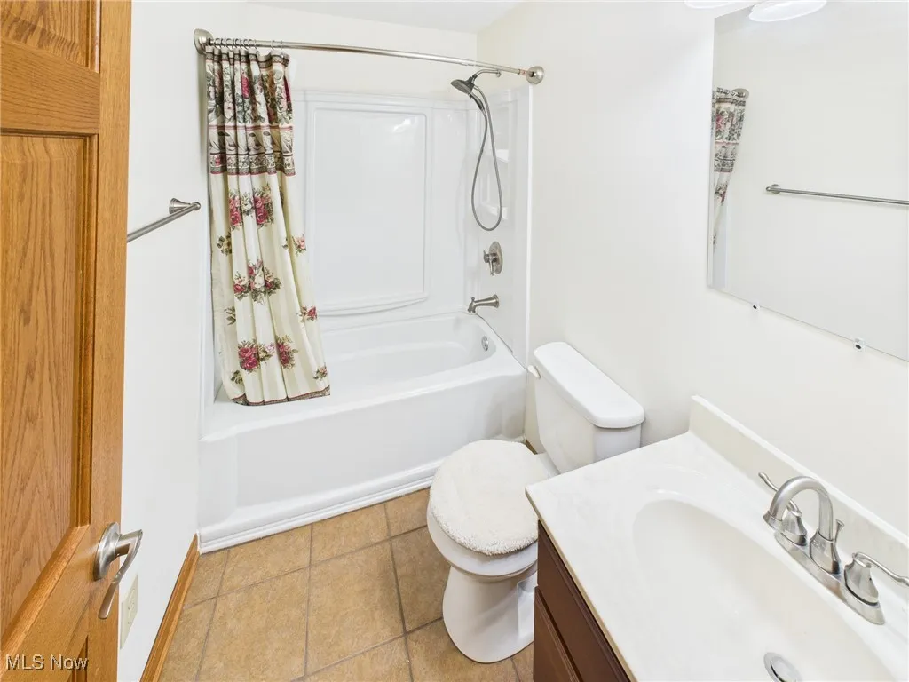 Bathroom with shower / bath combo with shower curtain, vanity, and light tile patterned floors