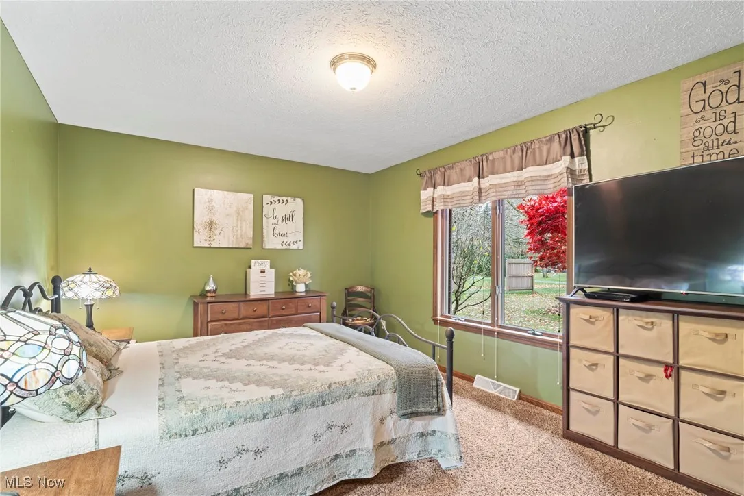 Carpeted bedroom with a textured ceiling and baseboards