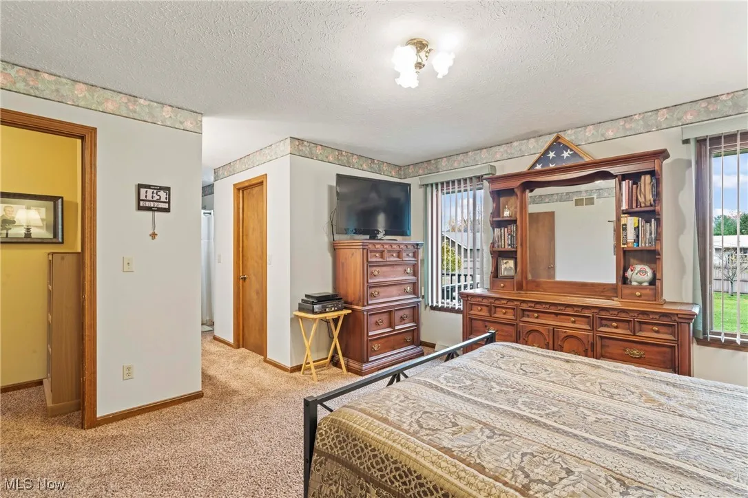 Bedroom featuring light colored carpet and a textured ceiling