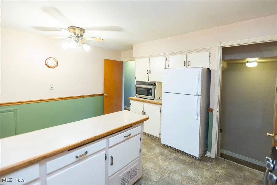 Kitchen with white cabinets, appliances with stainless steel finishes, light countertops, and ceiling fan