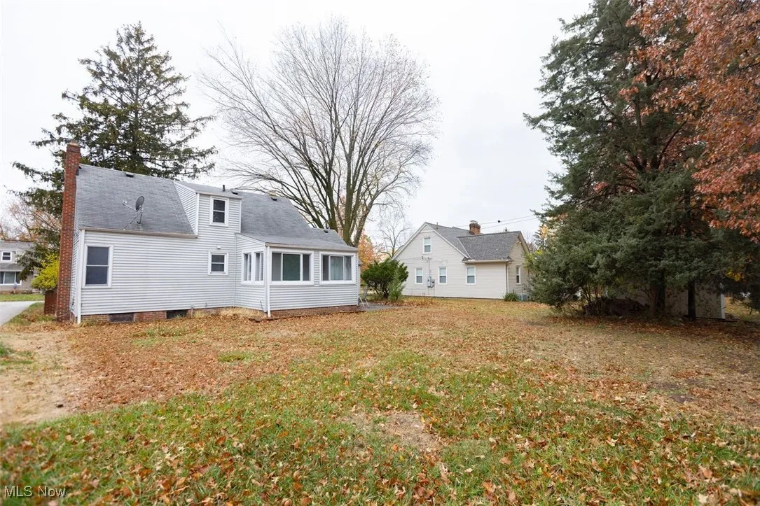 Rear view of property with a chimney and a lawn
