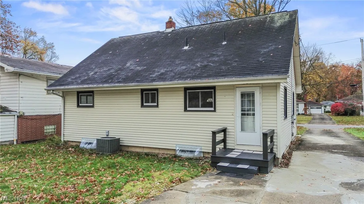 Rear view of property featuring roof with shingles and a chimney