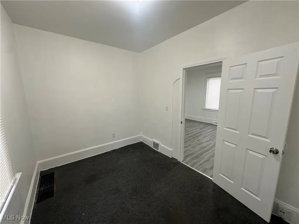 Empty room featuring dark colored carpet and baseboards
