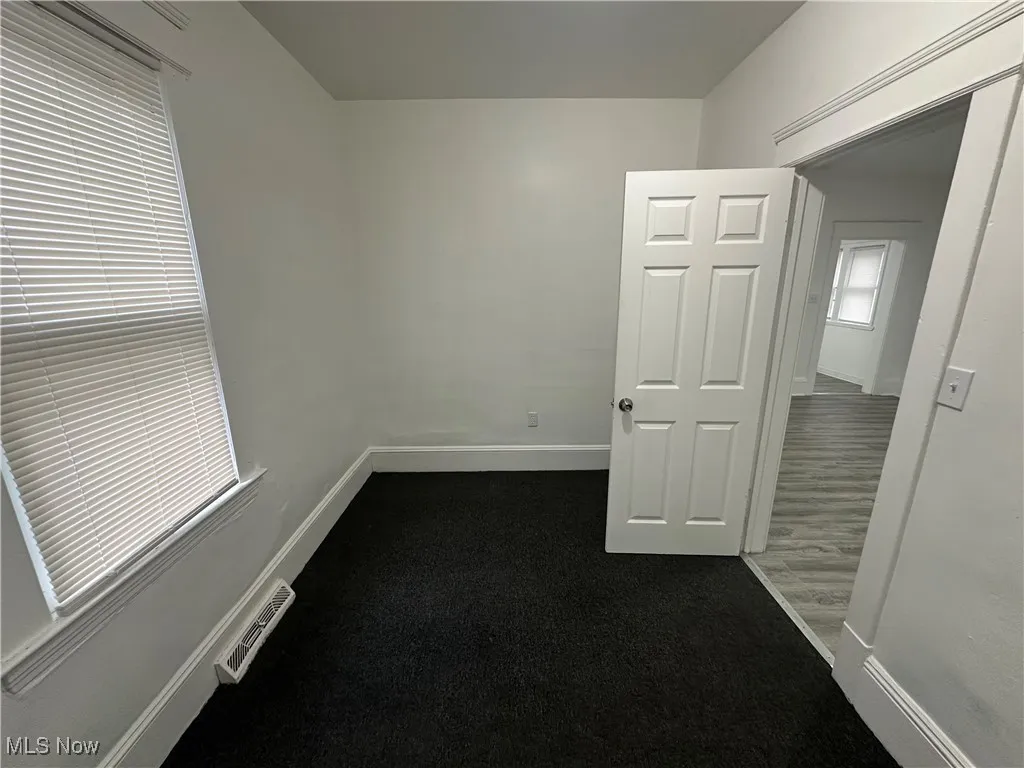 Spare room with dark colored carpet and baseboards