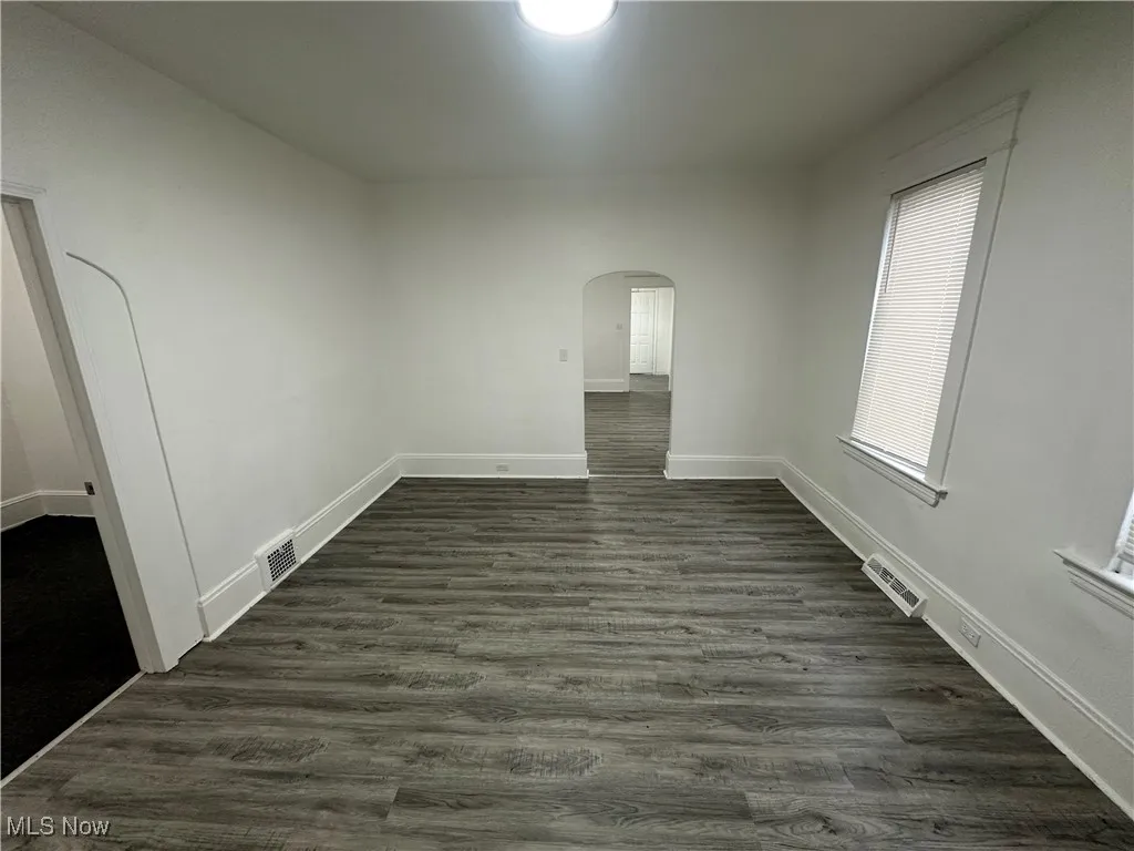 Spare room with arched walkways and dark wood finished floors