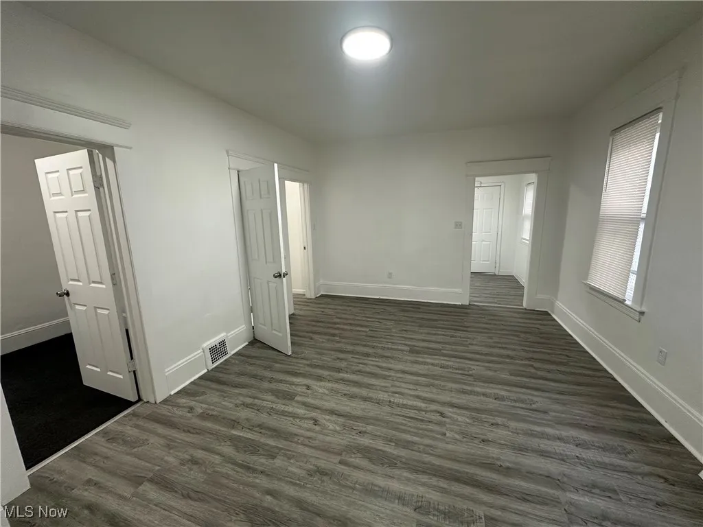 Empty room with dark wood-style flooring and baseboards