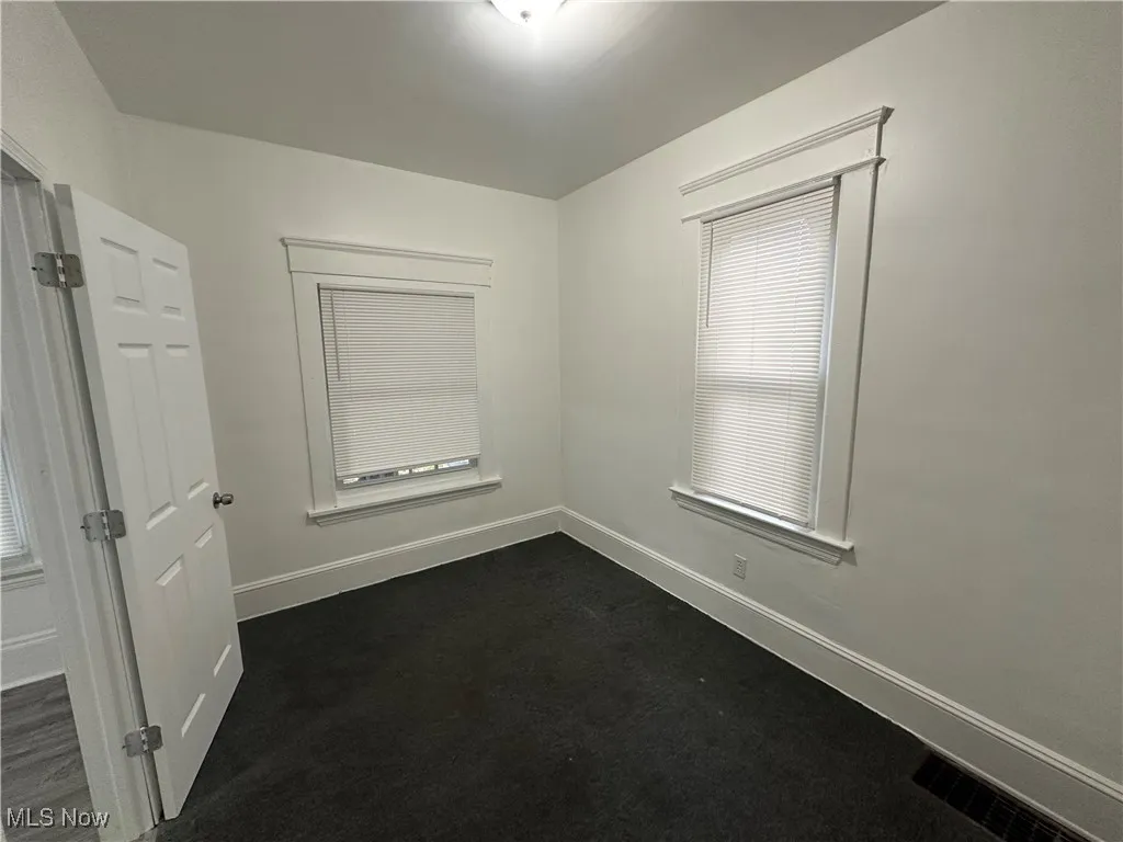 Spare room featuring dark carpet and healthy amount of natural light