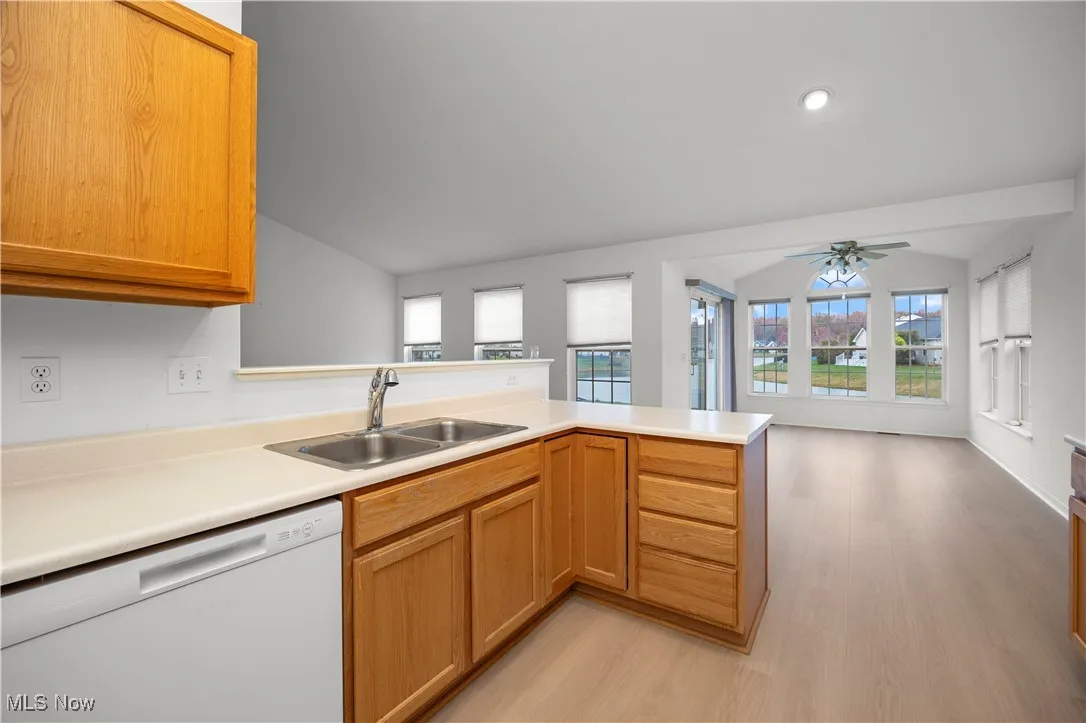 Kitchen with dishwasher, a peninsula, light countertops, light wood-style floors, and plenty of natural light