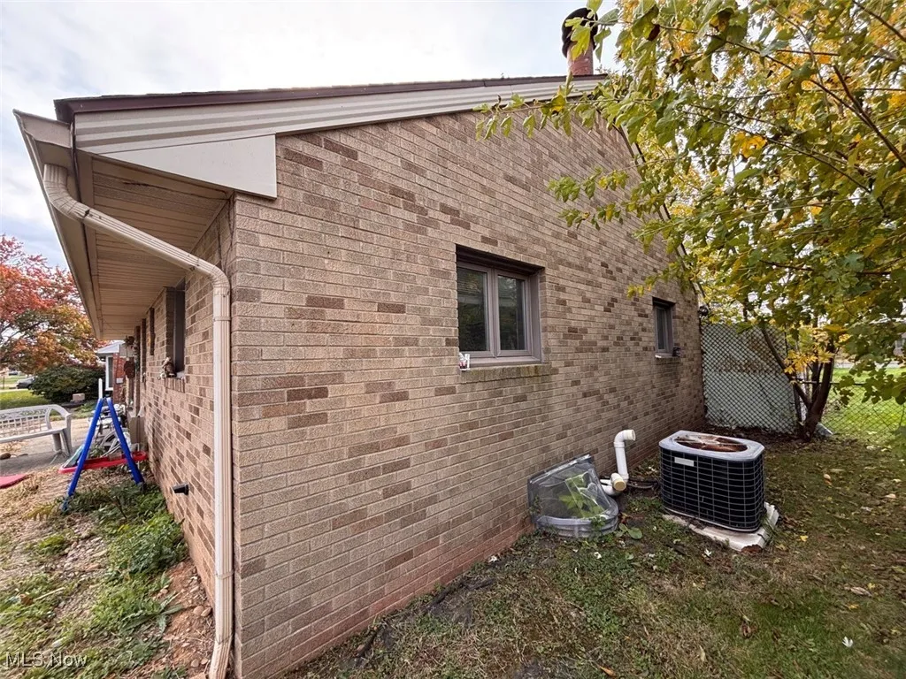 View of property exterior featuring brick siding and a central AC unit
