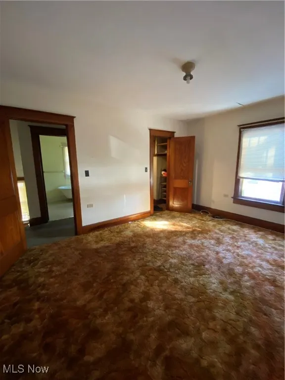 Carpeted spare room featuring baseboards