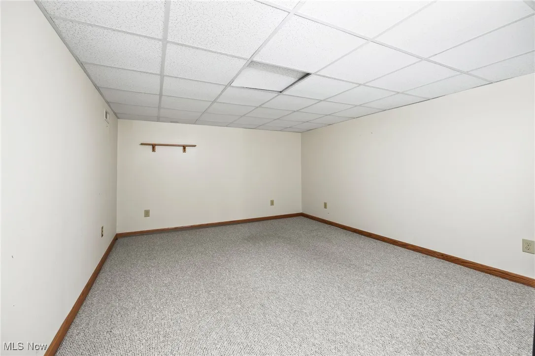 Carpeted empty room with baseboards and a drop ceiling