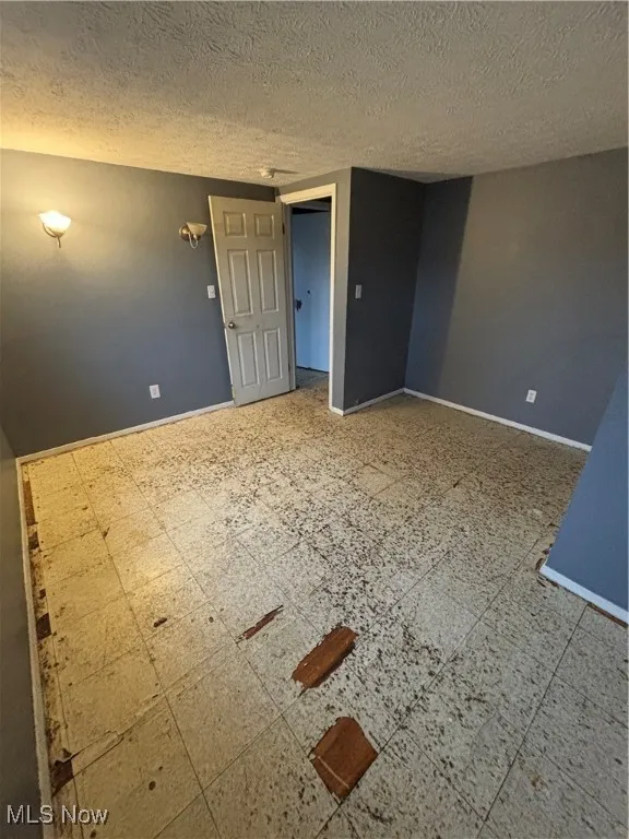 Empty room with a textured ceiling and tile patterned floors