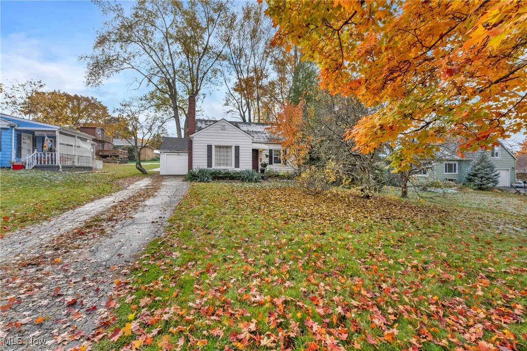 View of front of home with a front yard, driveway, an outbuilding, and a garage