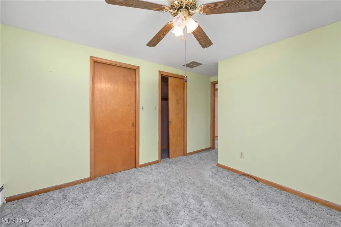 Unfurnished bedroom with carpet flooring, multiple closets, and ceiling fan