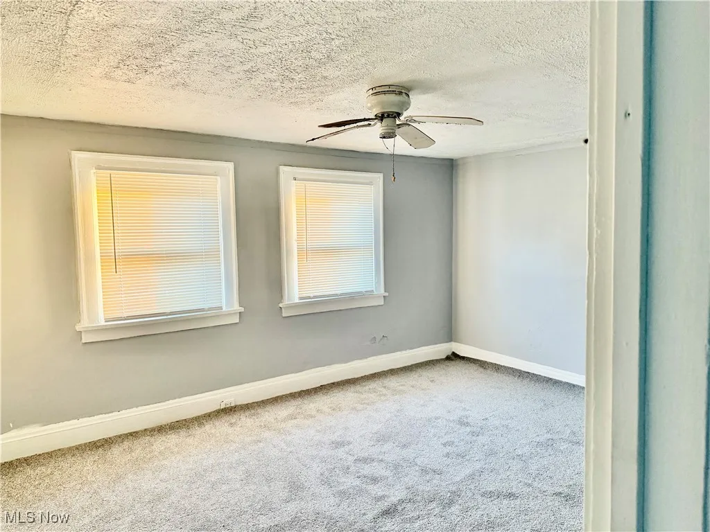 Carpeted spare room with a textured ceiling and a ceiling fan
