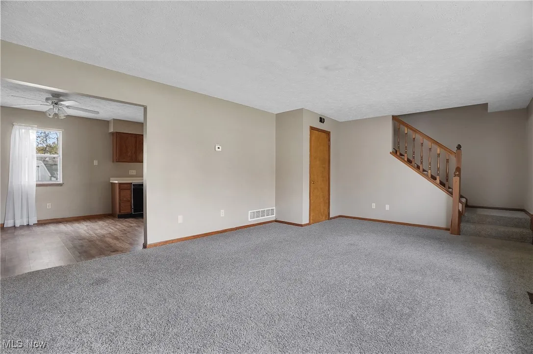 living room with a textured ceiling, stairs, carpet,