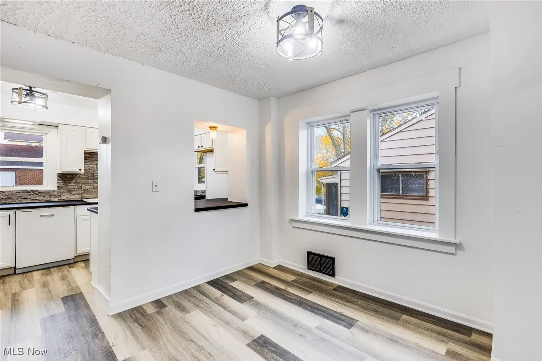 Unfurnished dining area with a textured ceiling and light wood-type flooring