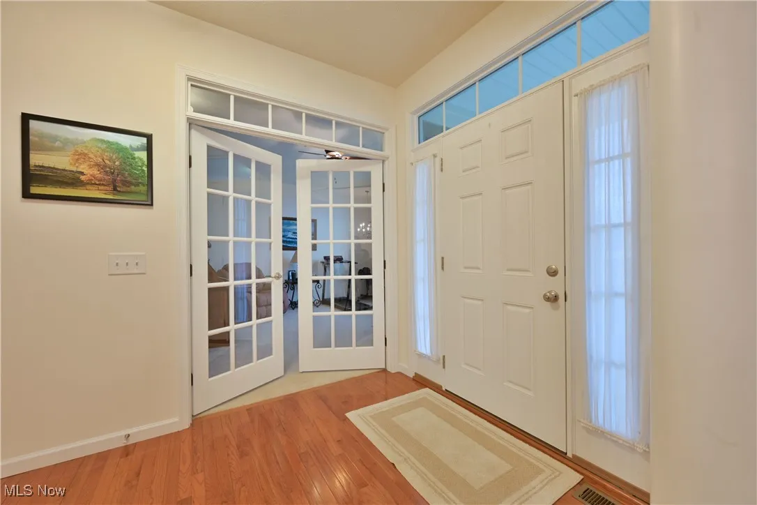 Foyer with french doors, light wood finished floors, a ceiling fan, and plenty of natural light