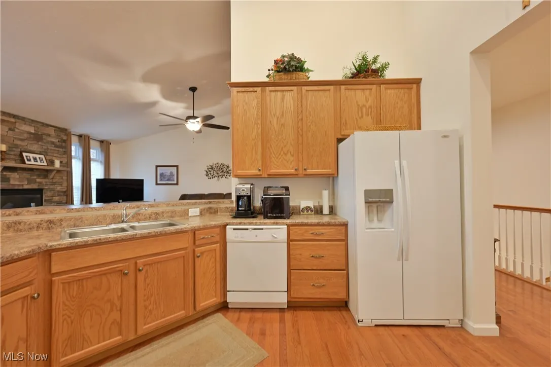 Kitchen featuring white appliances, open floor plan, light wood-type flooring, light countertops, and lofted ceiling
