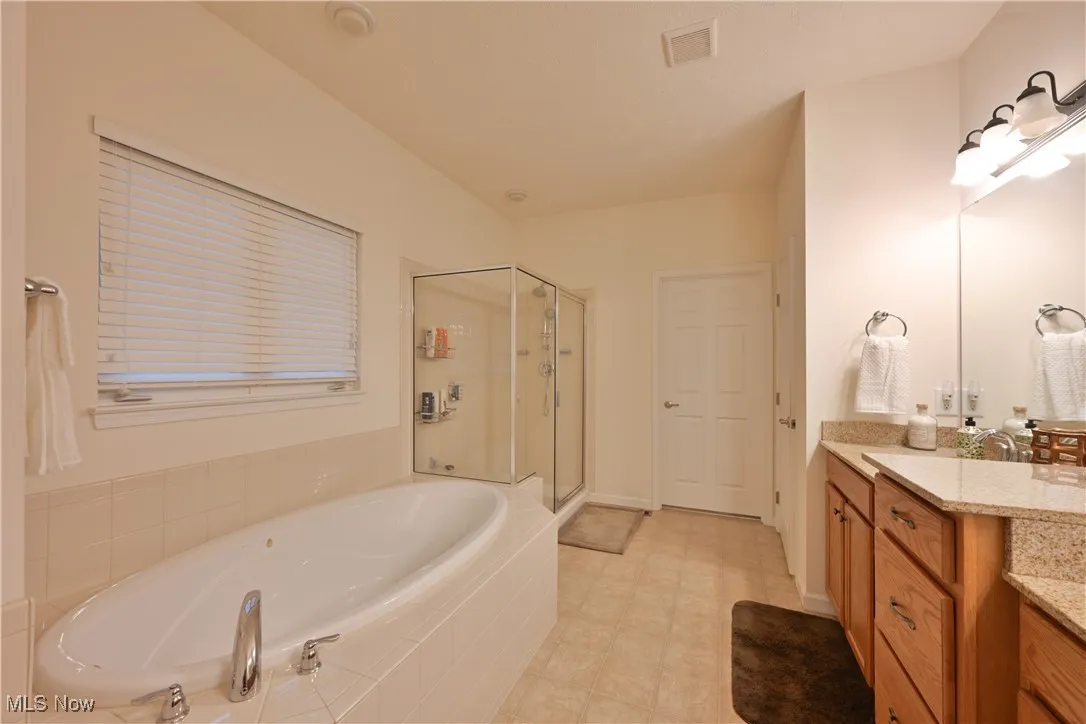 Full bathroom with vanity, a bath, and a shower stall
