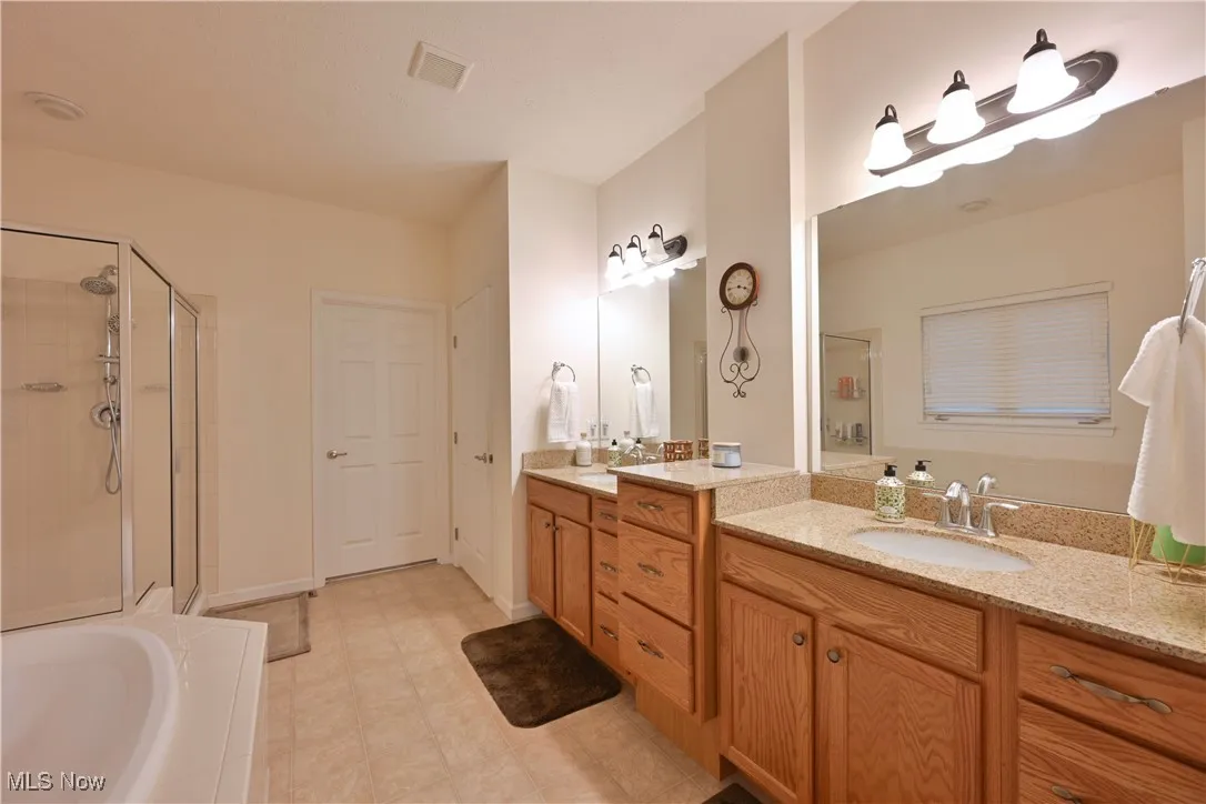 Full bathroom featuring a stall shower, a bath, and vanity