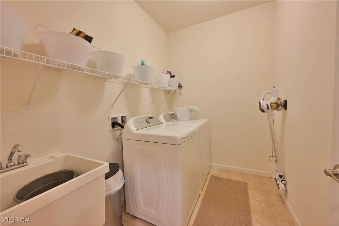 Laundry room with light tile patterned flooring, washing machine and clothes dryer, and a textured ceiling