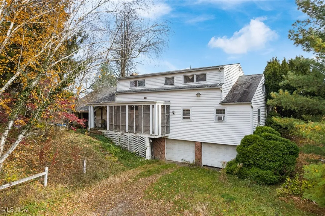 Rear view of property featuring a sunroom, an attached garage, and driveway