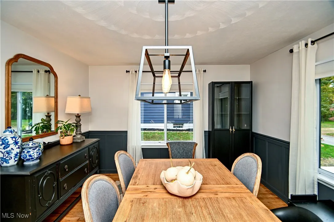 Dining area with a wainscoted wall, wood finished floors, and a decorative wall