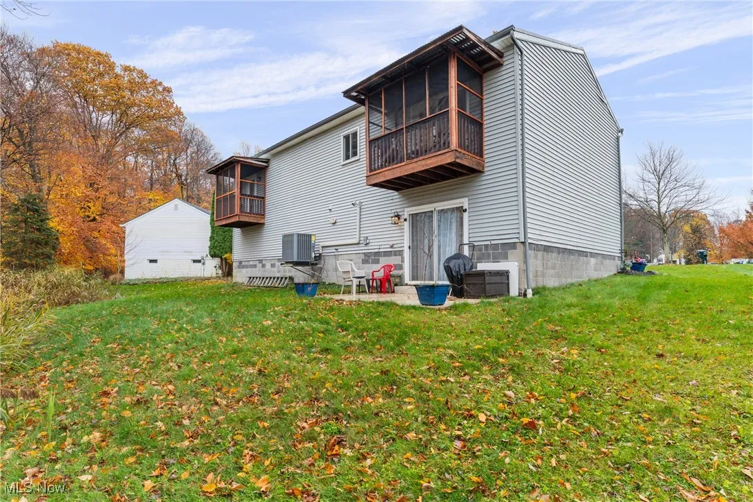 Back of house featuring a patio, a sunroom, and a yard
