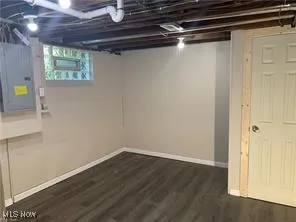 Basement with dark wood-style flooring and electric panel
