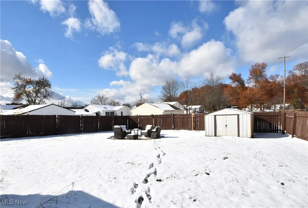 Fenced in backyard, a storage shed, a fire pit, and a residential view