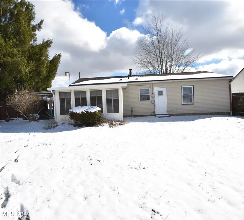 Snow covered house featuring a sunroom