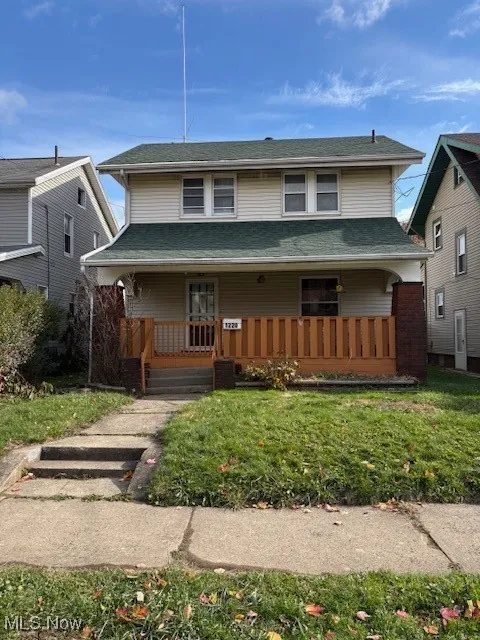 View of front of house with a porch, a front lawn, and a shingled roof