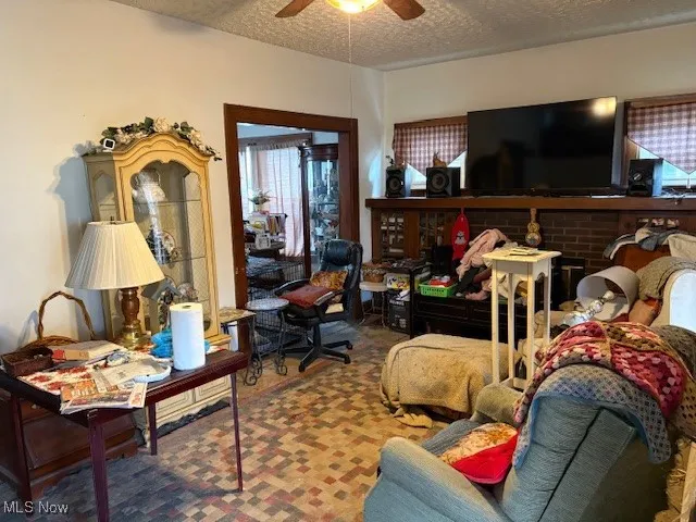 Carpeted living room featuring a textured ceiling and ceiling fan