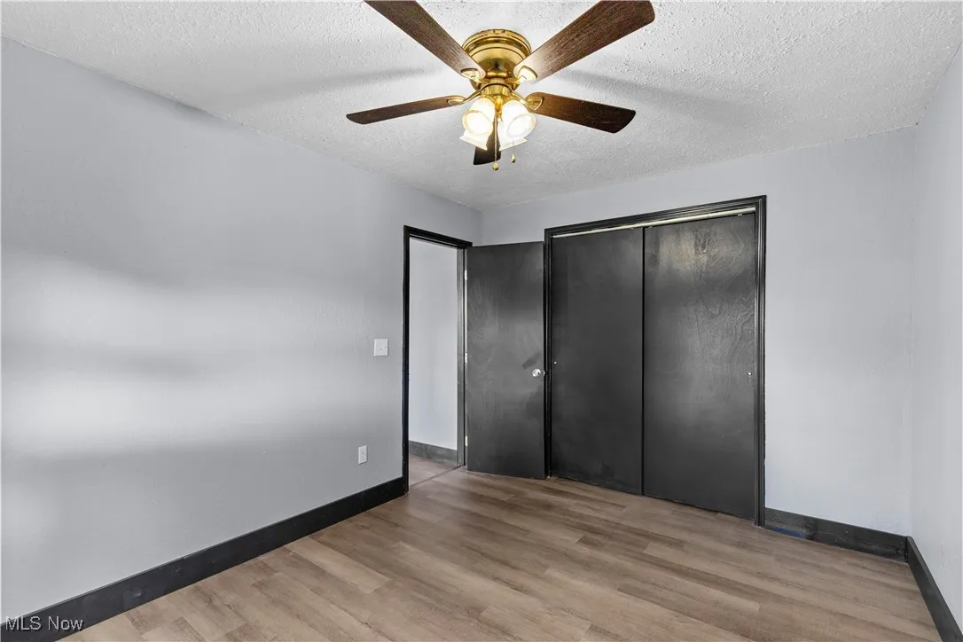 Unfurnished bedroom featuring a textured ceiling, light wood-style flooring, ceiling fan, and a closet