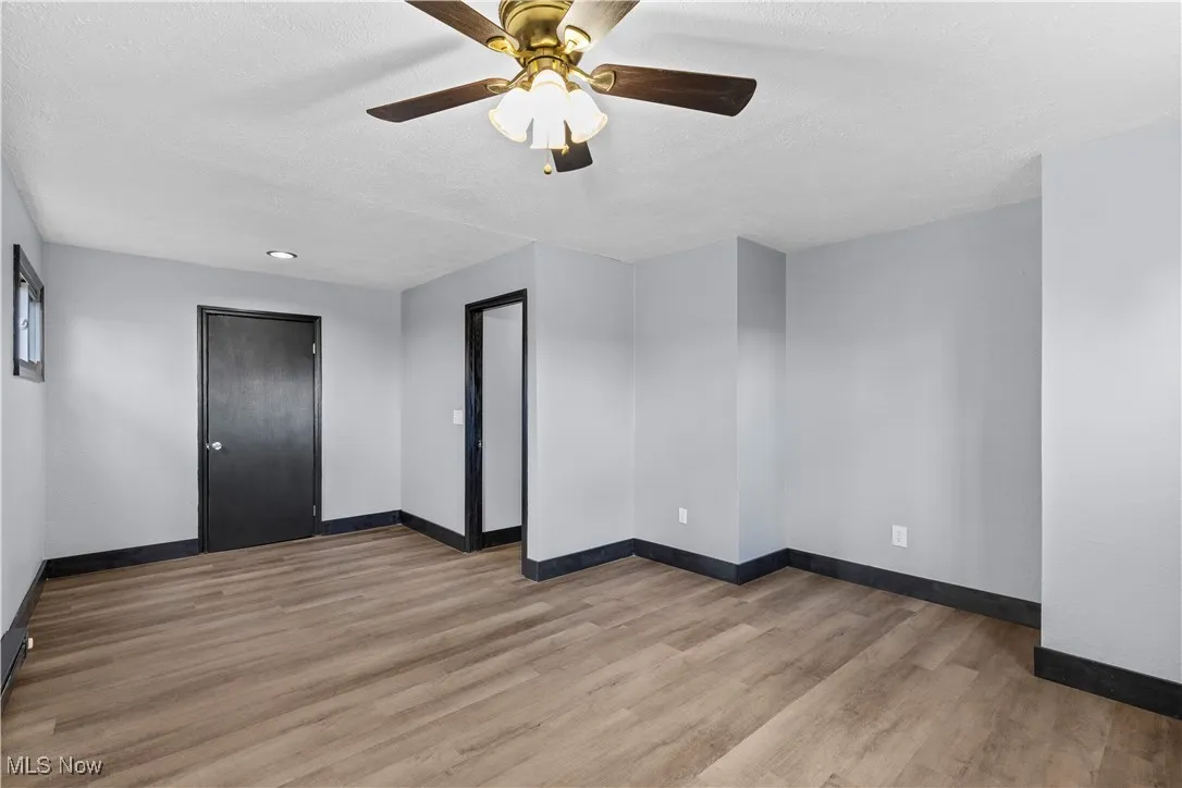 Empty room with light wood-style floors, a textured ceiling, and ceiling fan