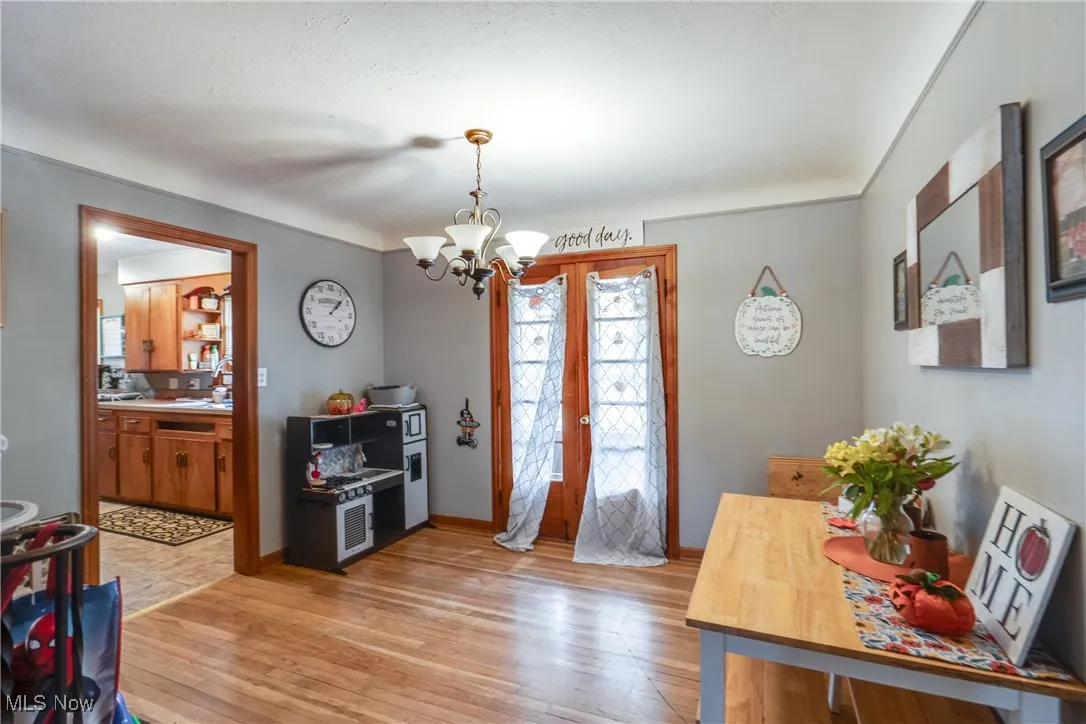 Dining area with light wood-style flooring, a chandelier, and french doors