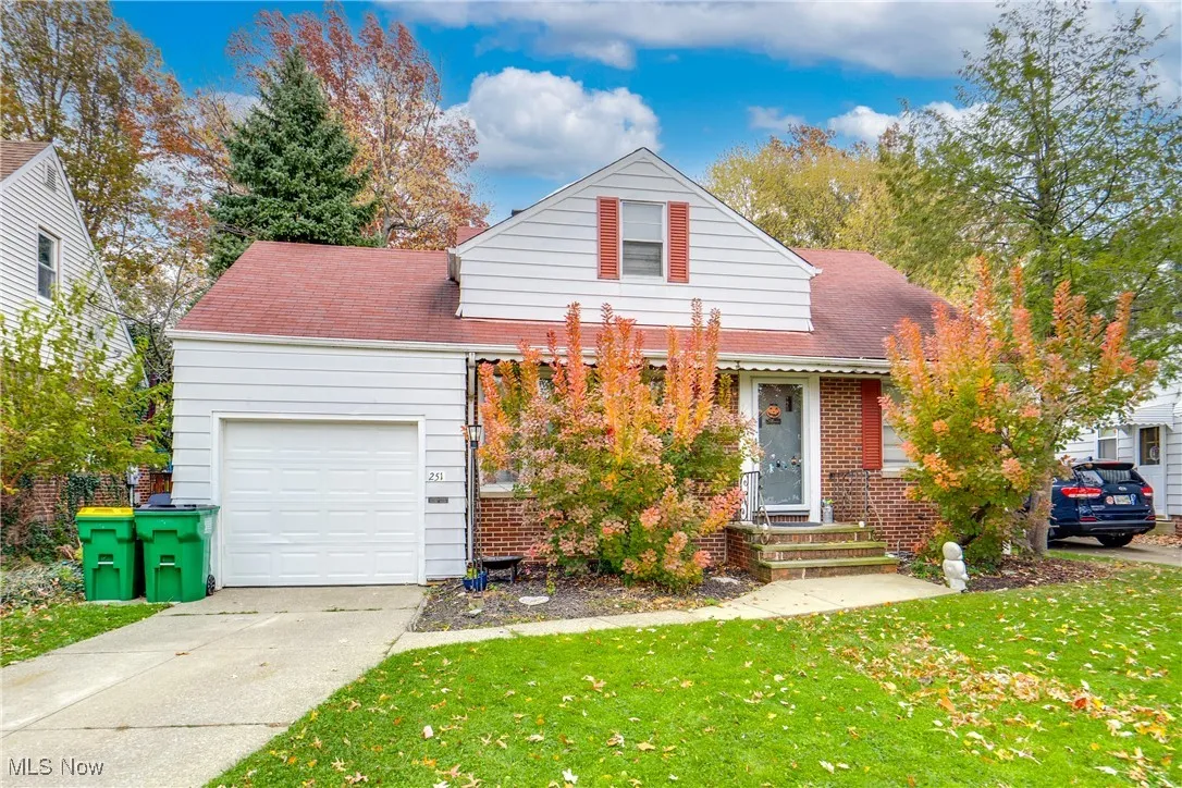 View of front facade featuring a front lawn, a shingled roof, brick siding, an attached garage, and concrete driveway
