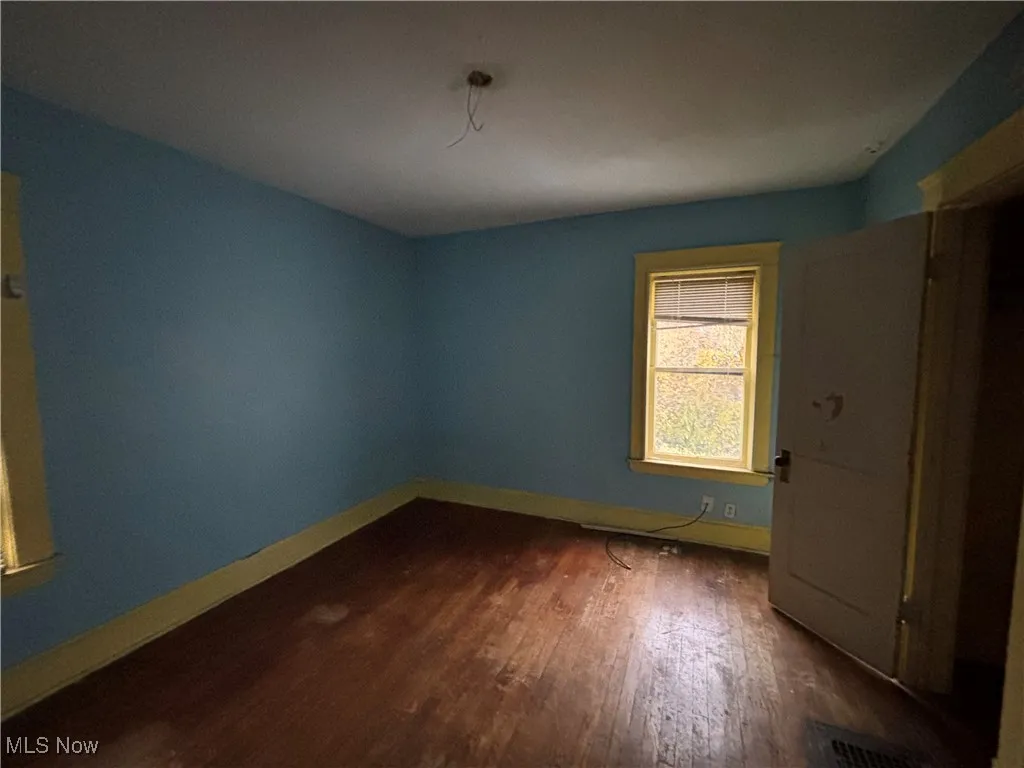 Unfurnished bedroom with dark wood finished floors and baseboards