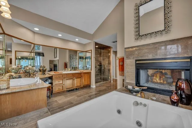 View of fireplace, vaulted ceiling, walk in shower and custom made cabinetry.