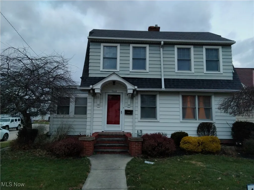 View of front of house featuring a chimney, a front lawn, and roof with shingles