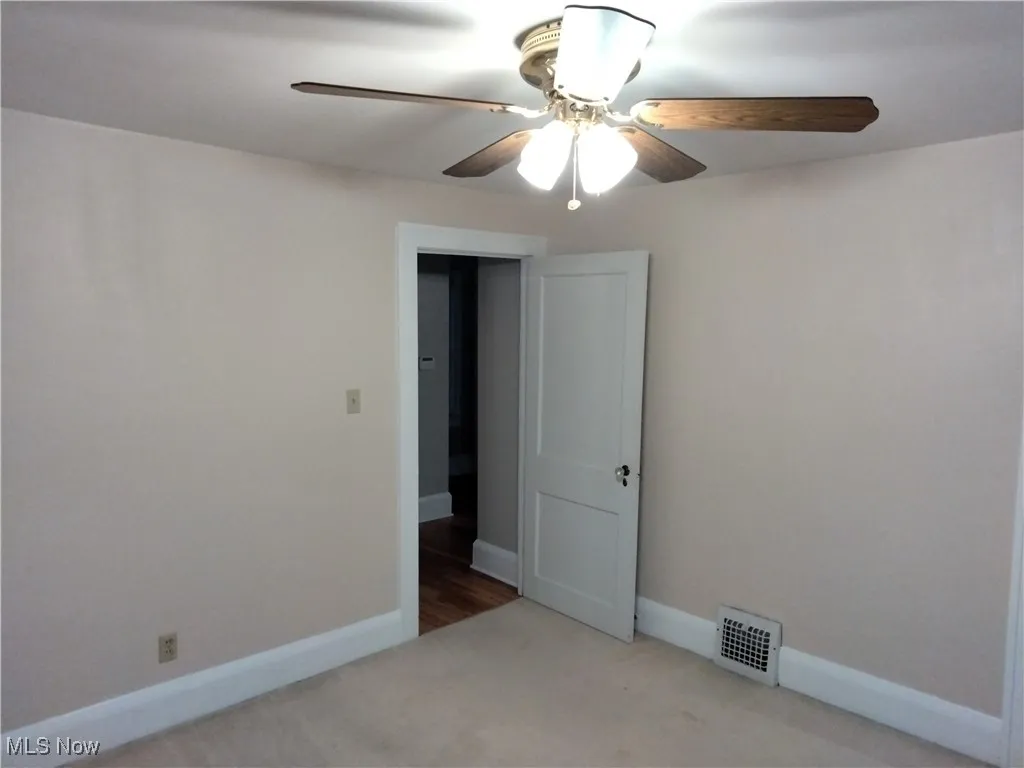 Spare room featuring light carpet and ceiling fan