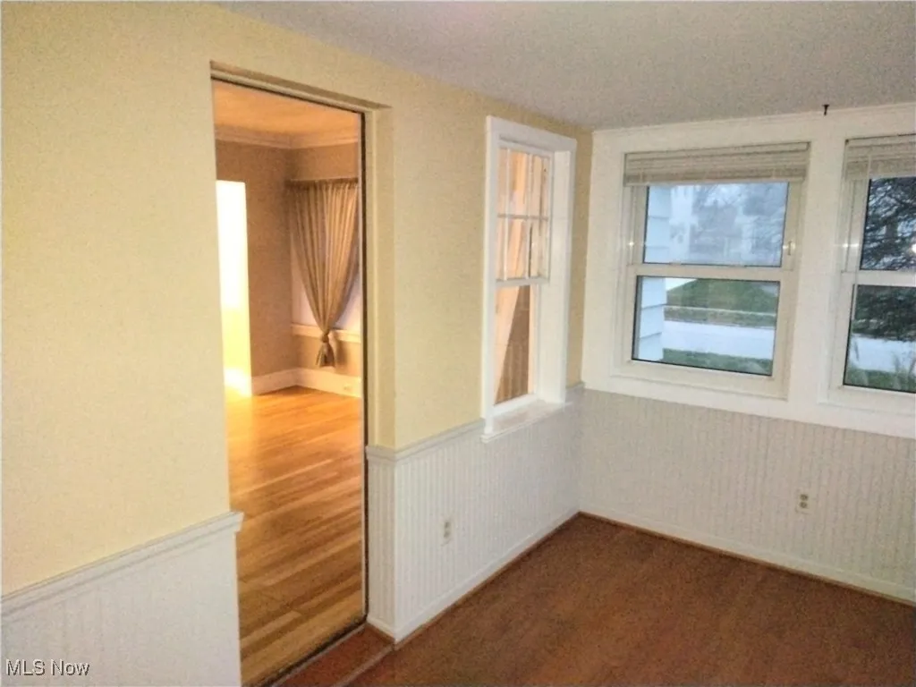 Empty room featuring wainscoting, ornamental molding, and dark colored carpet