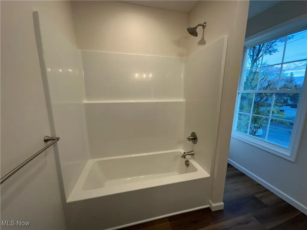 Bathroom featuring  shower combination and dark wood-type flooring
