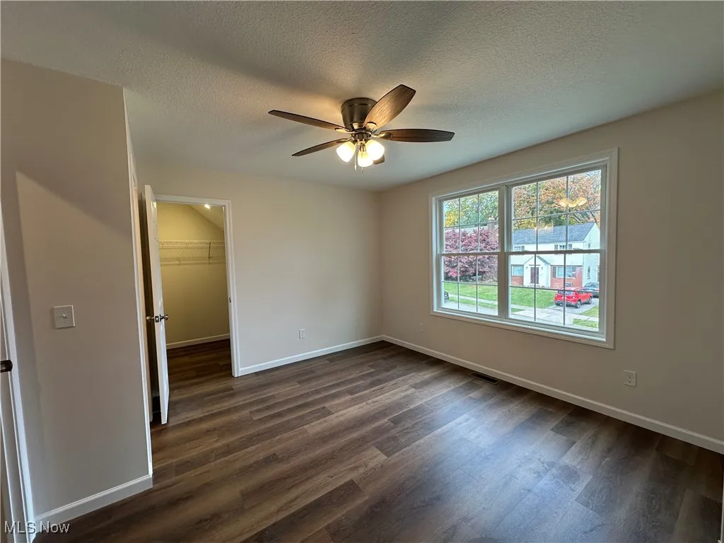 Unfurnished bedroom with dark wood-style flooring, a textured ceiling, and ceiling fan